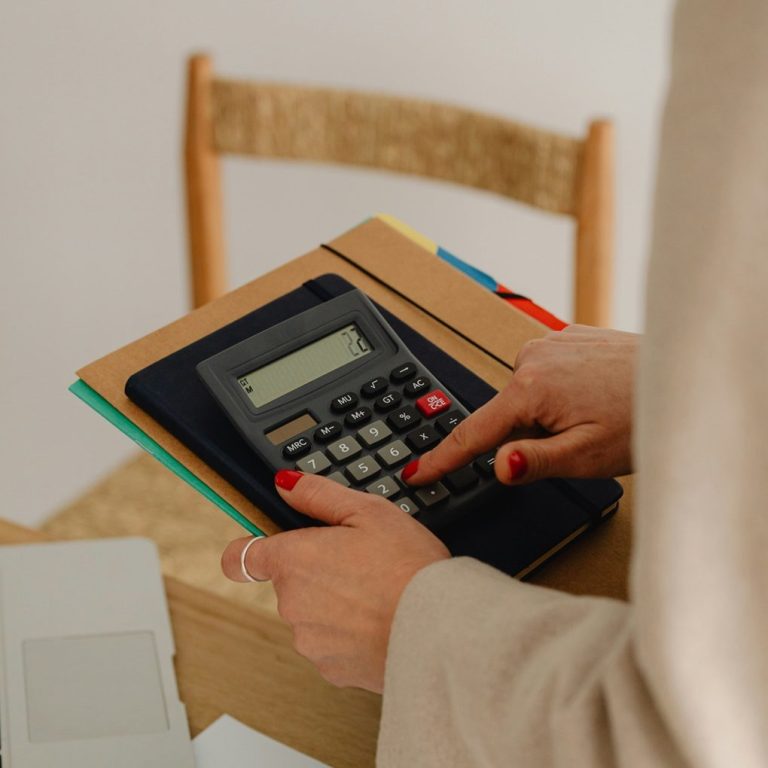 kobieta z zadbanymi paznokciami liczy coś na kalkulatorze